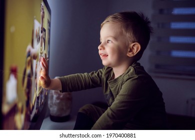 A bedtime ritual for toddlers. The boy touched the TV screen with one hand. A close-up shot of a kid in pajamas sitting right in front of the TV and staring at a cartoon Watching favorite cartoon show - Shutterstock ID 1970400881