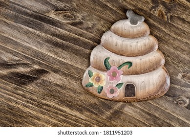 Bee hive ornament with flowers and a front door isolated on a walnut colored wood grain background.