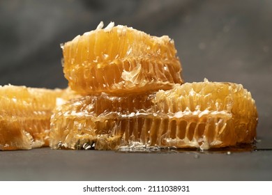 Bee Honeycomb Wax With Honey On Black Background. Honey Dripping From Honey Comb Close Up.