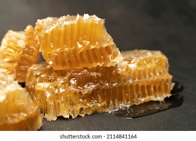 Bee Honeycomb Wax With Honey On Black Background. Honey Dripping From Honey Comb Close Up.