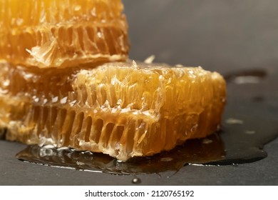 Bee Honeycomb Wax With Honey On Black Background. Honey Dripping From Honey Comb Close Up.