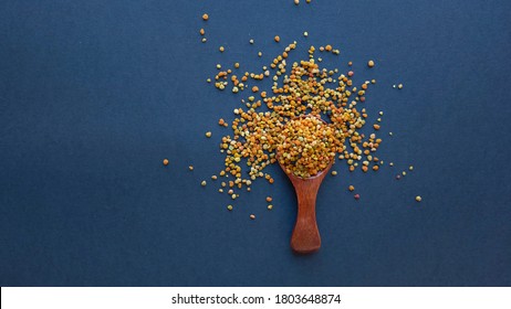 Bee Pollen In A Wooden Spoon Healthy Food Supplements. Close Up On A Black Background. Top View, Flat Lay. Copy Space For Text.