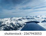 Beechcraft Bonanza airplane wingtip flies over Lake Clark Pass in Alaska. Mount Redoubt in the background. Small aircraft are only way to see many areas of Alaska.
