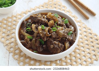 beef with black pepper sauce or sapi lada hitam is stir fried beef with onion, bell pepper in black pepper sauce. sprinkled scallions and sesame seeds. served on white plate. selected focus 