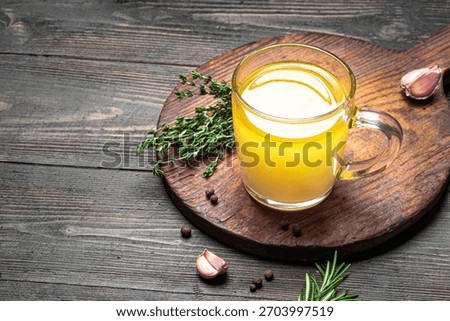Beef bone broth with herbs (instant bouillon) in mug on dark wooden background, side view. Healthy food, drink collagen broth.