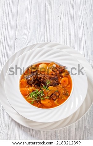 Beef Bourguignon, Beef Burgundy, stew with beef, bacon, carrots, onions and mushrooms slow cooked in rich red wine sauce in white bowl, french cuisine, vertical view, free space