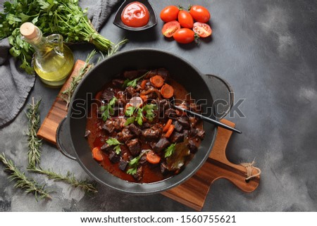 Beef Bourguignon in a pan. Stew  with red wine ,carrots, onions, garlic, a bouquet garni, and garnished with pearl onions, mushrooms and bacon. French cuisine- regional recipe from Burgundy