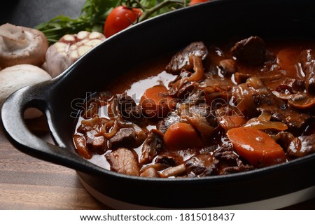 Beef Bourguignon in a pan. Stew with red wine ,carrots, onions, garlic, a bouquet garni, and garnished with pearl onions, mushrooms and bacon. French cuisine- regional recipe from Burgundy