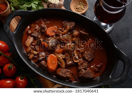 Beef Bourguignon in a pan. Stew with red wine ,carrots, onions, garlic, a bouquet garni, and garnished with pearl onions, mushrooms and bacon. French cuisine- regional recipe from Burgundy