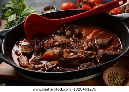 Beef Bourguignon in a pan. Stew with red wine ,carrots, onions, garlic, a bouquet garni, and garnished with pearl onions, mushrooms and bacon. French cuisine- regional recipe from Burgundy