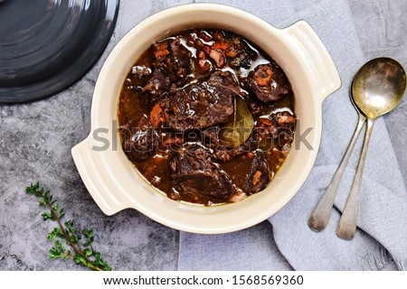Beef bourguignon in the pot on the grey background, top view