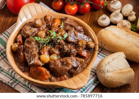Beef Bourguignon stew served with baguette on dish. French cuisine