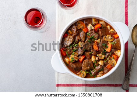 Beef bourguignon stew with vegetables and red wine. Grey background. Top view.