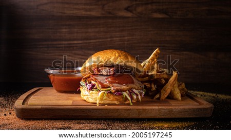 beef brisket burger in a Bun brioche with pickles and sauce on a wooden background on a wooden cutting board