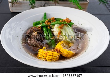Beef Bulalo, a popular a beef soup dish from the Philippines. It is a light colored soup with beef shanks and marrow.