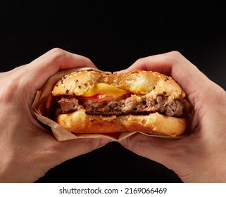 A beef burger with a bite in hand