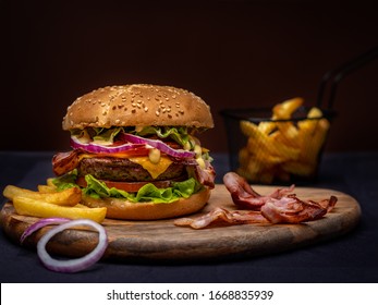 Beef burger and french fries on wooden table isolated on black background