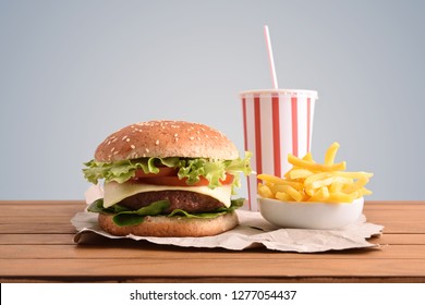 Beef Burger,chips And Soda On Wooden Table With Golden Backgorund. Front View. Horizontal Composition.