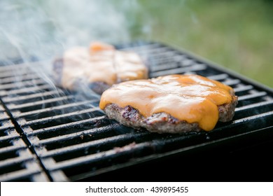 Beef Burgers Covered With Cheese On A Smoky Grill