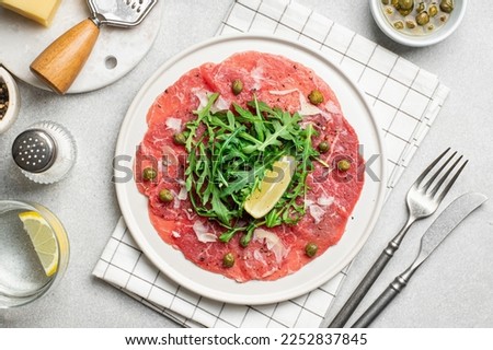 Beef carpaccio with capers, arugula and parmesan on the table, flat lay