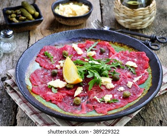 beef carpaccio with capers, parmesan, arugula, lemon and olive oil.