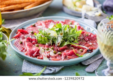 Beef carpaccio on black plate with mustard and parmesan