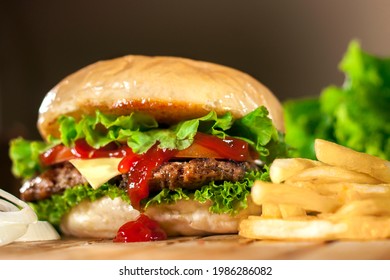 Beef and Cheese Burger in a brown background. Tasty homade hamburger mix with french fries, union and salad. Side view