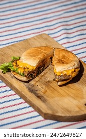 a beef cheese burger that is split with a knife filled with meat, tomato sauce, mayonnaise and lettuce that looks delicious and tempting to make your stomach hungry
