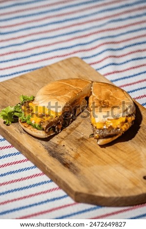 a beef cheese burger that is split with a knife filled with meat, tomato sauce, mayonnaise and lettuce that looks delicious and tempting to make your stomach hungry