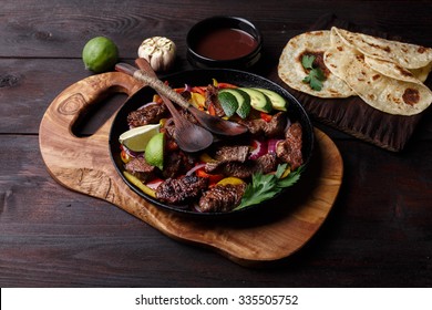 Beef fajita with bell peppers. Tortillas, avocado, sauce served with grilled beef and vegetables on skillet. Tex-mex cuisine
