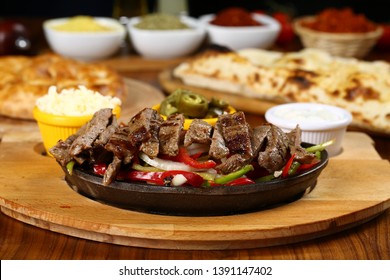 Beef Fajitas with colorful bell peppers in pan, tortilla and sauces