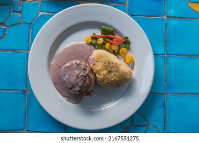 Beef Fillet Wrapped In Bacon, Stuffed With Blue Cheese, On A Red Wine Sauce, Accompanied By Mashed Potatoes And Salad, Mexican Gourmet Food. On A Blue Background