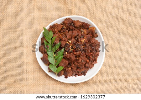 Beef fry curry or mutton fry Kerala India special hot spicy traditional Christian feast dish, jute background. Buffalo roast, meat pepper fry. Top view South Indian non veg food side dish Rice, Appam.