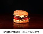 beef hambuger with bun with sesame lettuce tomato cheddar cheese on wooden table on dark background