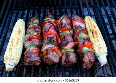 Beef Kabobs On The Grill Along With Corn On The Cob