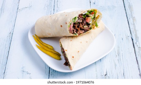 Beef lavash doner kebab sliced in plate isolated on white wood table.