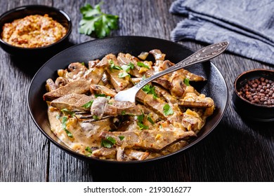 Beef Liver Stroganoff With Wholegrain Mustard, Onion And Mushrooms In Black Bowl On Dark Wooden Table, Horizontal View From Above