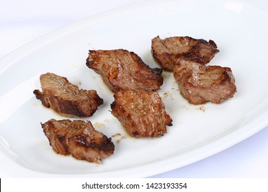 Rindfleischwürfel auf Teller auf weißem Hintergrund