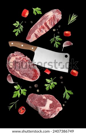 Beef meat, different spices and cleaver knife falling on black background