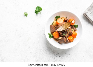 Beef Meat Stewed With Potatoes, Carrots And Spices On White Background, Top View, Copy Space. Homemade Winter Comfort Food - Slow Cooked Meat Stew.