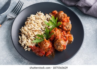 Rindfleisch-Kugeln und brauner Reis auf einem Teller. Fertiggerichte aus portioniertem Fleisch mit Garnisch.