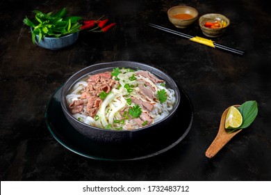 Beef Noodle Or Pho Bo In A Cooking Class Dark Kitchen Table. Food Is Herb In Delicious Broth. Serving With Chili, Chili Sauce, Lime. Best Street Food Of Vietnam 