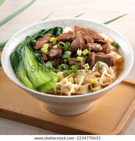 Beef noodle soup. Taiwanese famous food with sliced red braised beef and vegetables in a bowl on wooden table background.