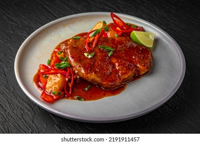 Beef Or Pork Steak With Stewed Vegetables And Sauce In A Ceramic Plate On A Dark Textured Background. Restaurant Menu Isolated On Black