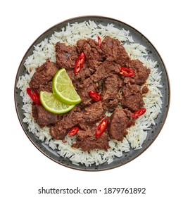 Beef Rendang on black plate isolated on white. Indonesian padang cuisine meat dish. Asian food. Top view