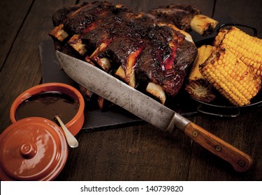 Beef Ribs Cooked On The BBQ And Served With Sweetcorn And A Red Wine Souse. Barbequed Beef Ribs And Corn.