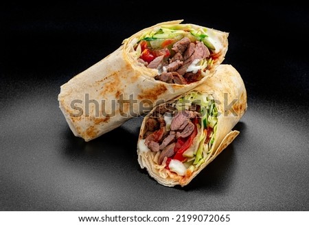Beef shawarma on a dark background. Shawarma with beef in pita bread. Photo for the menu