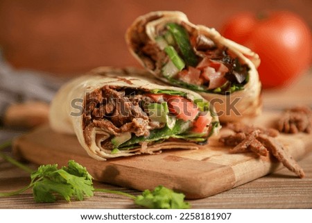 Beef shawarma sandwich fresh roll, wrap of grilled meat and salad tortilla wrap with white sauce. turkish Doner Kebab on a lavash - Shawarma Beef.

