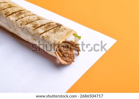 Beef Shawarma Wrap in Syrian Bread – 45 Degree Angle on Orange and White Background
A beef shawarma sandwich wrapped in traditional Syrian flatbread, photographed at a 45-degree angle 