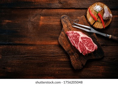 Beef Shoulder Steak On A Wooden Table With Garlic And Red Pepper, Top View And Copy Space